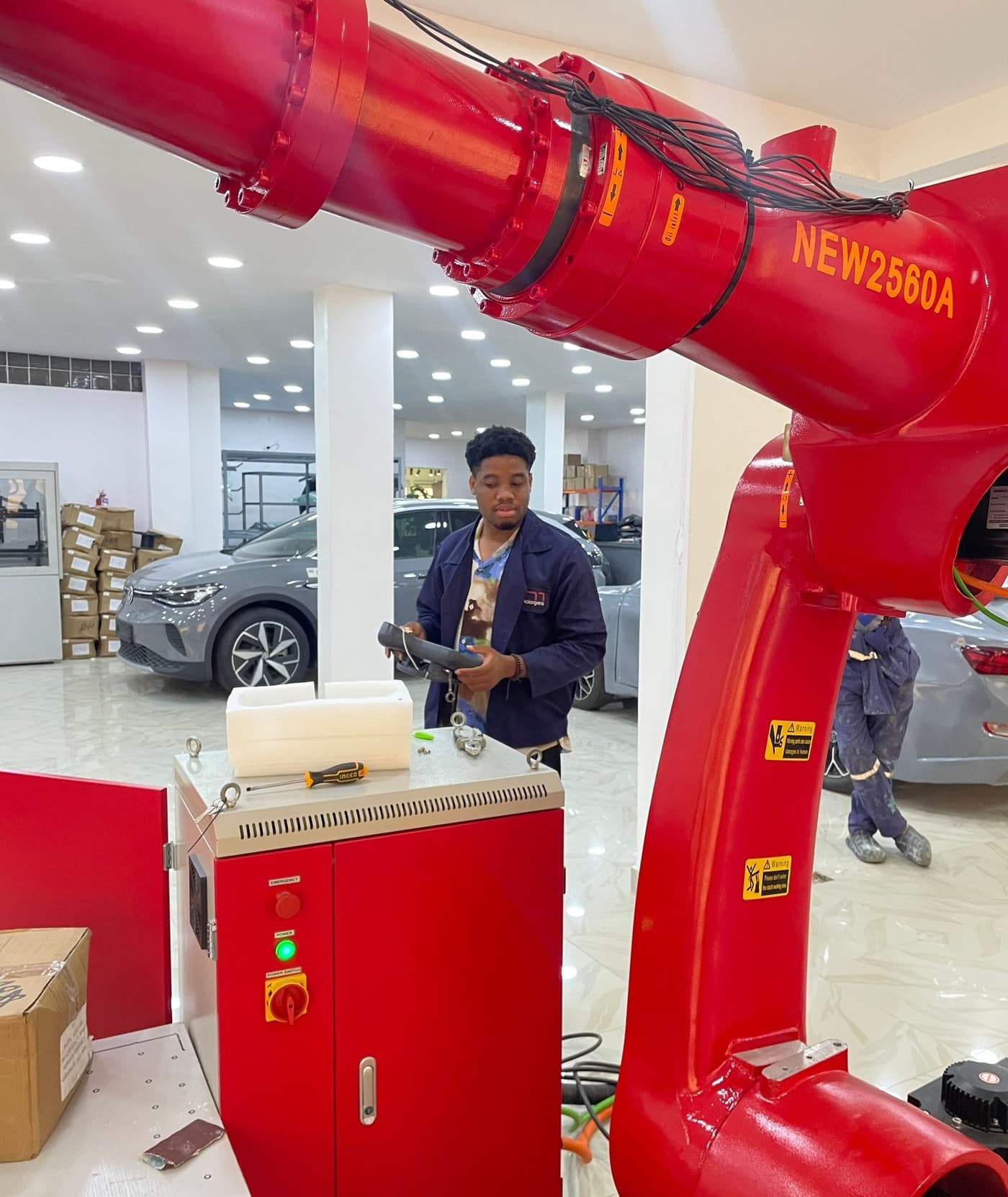 Chibuike operating a 6-axis industrial robot arm controller in a robotics workshop